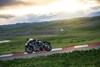 Profile angle of a person riding a motorcycle through a corner on a track.