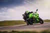 Three-quarter front angle of a person on a green motorcycle leaning into a corner on a track.