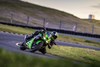 Three-quarter front angle of a person on a motorcycle leaning into a corner on a track.