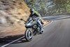Three-quarter front angle of a person riding a gray motorcycle on a road.