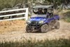 Three-quarter front angle of a person and passenger driving a side x side on a trail.