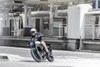 Three-quarter front angle of a person riding a motorcycle on a street.