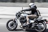 Profile angle of a person riding a motorcycle on a road.