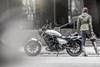Side angle of a person next to a motorcycle.