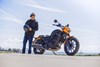 Side angle of a person standing next to a motorcycle.