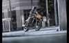 Three-quarter front angle of a person riding a motorcycle in the city.