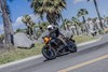 Three-quarter front angle of a person riding a motorcycle on the street.