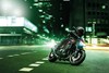 Three-quarter front angle of a person riding a red motorcycle on a city street.