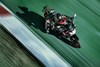 Aerial three-quarter front angle of a person riding a motorcycle on the racetrack.