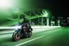 Three-quarter front angle of a person riding a motorcycle on a city street.
