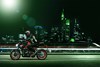 Side angle of a person riding a motorcycle on a city street.