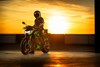 Three-quarter front angle of a person on a green motorcycle.
