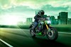 Three-quarter front angle of a person riding a motorcycle on a city street.