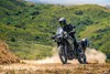 Three-quarter front angle of a person riding a motorcycle on an off-road trail.