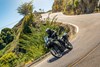 Three-quarter front angle of a person riding a motorcycle on a road.