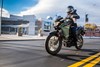 Three-quarter front angle of a person riding a motorcycle on a street.