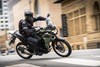 Side angle of a person riding a motorcycle on a city street.