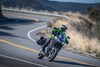 Three-quarter front angle of a person riding a motorcycle on a road.