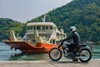 Profile angle of a person on a motorcycle parked near water.