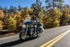 Three-quarter front angle of a person riding a black motorcycle on a road.