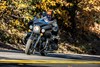 Three-quarter front angle of a person riding a motorcycle on a road.