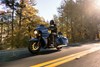 Side angle of a person riding a motorcycle on a road.