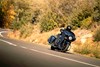 Three-quarter front angle of a person riding a motorcycle on a road.