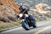 Three-quarter front angle of a person riding a motorcycle on a road.