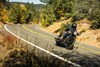 Three-quarter front angle of a person riding a motorcycle on a road.