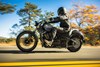 Side angle of a person riding a motorcycle on a road.