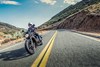 Three-quarter front angle of a person riding a motorcycle on a road.