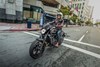 Three-quarter front angle of a person riding a motorcycle on a city street.