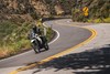 Three-quarter front angle of a person riding a motorcycle on a road.