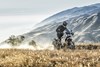 Three-quarter front angle of a person riding a motorcycle on an off-road trail.