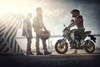 Side angle of a person on a parked motorcycle.