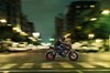 Side angle of a person riding a motorcycle on a city street.