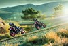 Side angle of a two people riding motorcycles around a bend on a road.