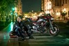 Side angle of a person seated next to a parked motorcycle.