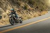 Three-quarter front angle of a person riding a motorcycle around a bend in a road.