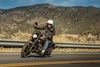 Three-quarter front angle of a person riding a motorcycle on a road.