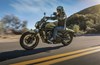 Side angle of a person riding a motorcycle on a road.