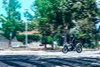 Profile angle of a person riding a motorcycle on a street.