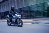 Three-quarter front angle of a person riding a motorcycle on a street.