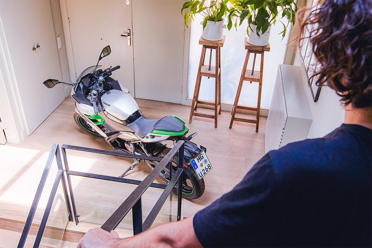 Three-quarter rear angle of a motorcycle staged in a house.