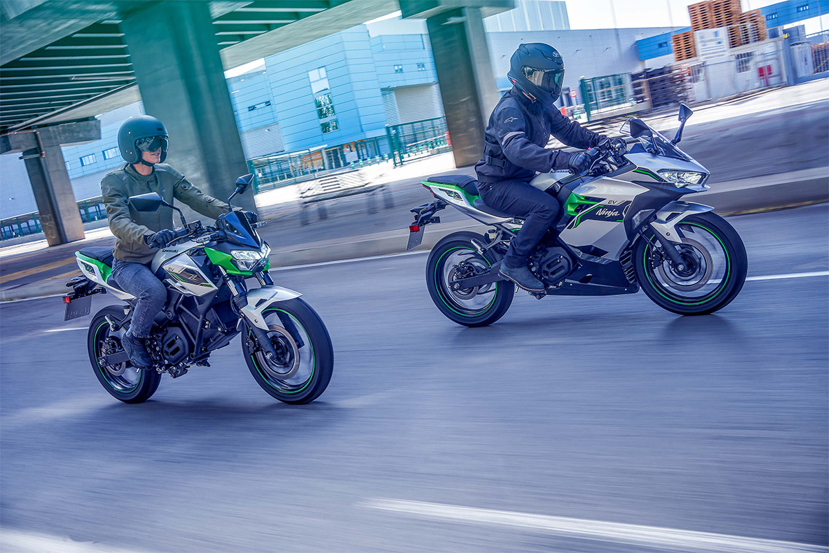 Three-quarter front angle of two people riding motorcycles on a road.