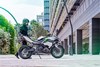 Side angle of a person approaching a parked motorcycle.