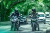 Front angle of two people on motorcycles on a city street.