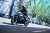 Side angle of a person riding a motorcycle on a street.