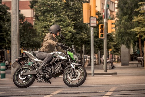 Profile angle of a person riding a motorcycle on a city street. opens in a new window