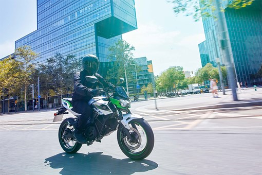 Three-quarter front angle of a person riding a motorcycle on a city street. opens in a new window